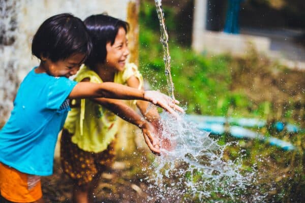 Two children playing with a water jet