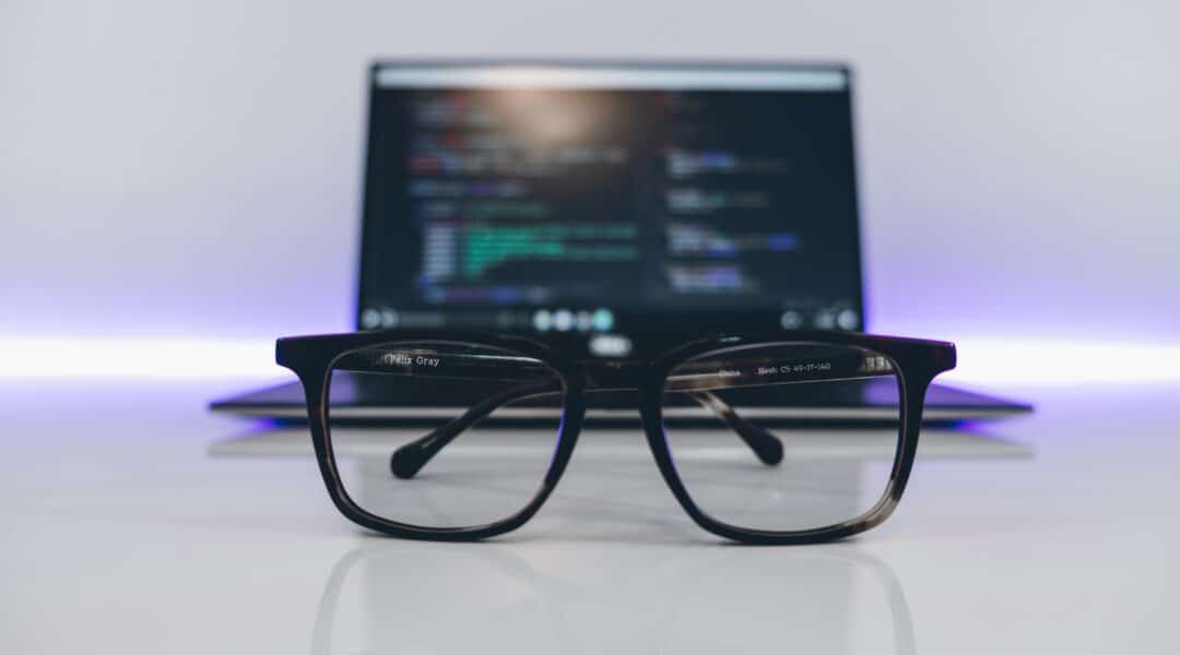 Glasses in front of a laptop which has code on it