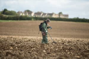 Woman using a metal detector in a field