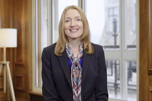 lady with blonde hair dressed smartly in a wood paneled office