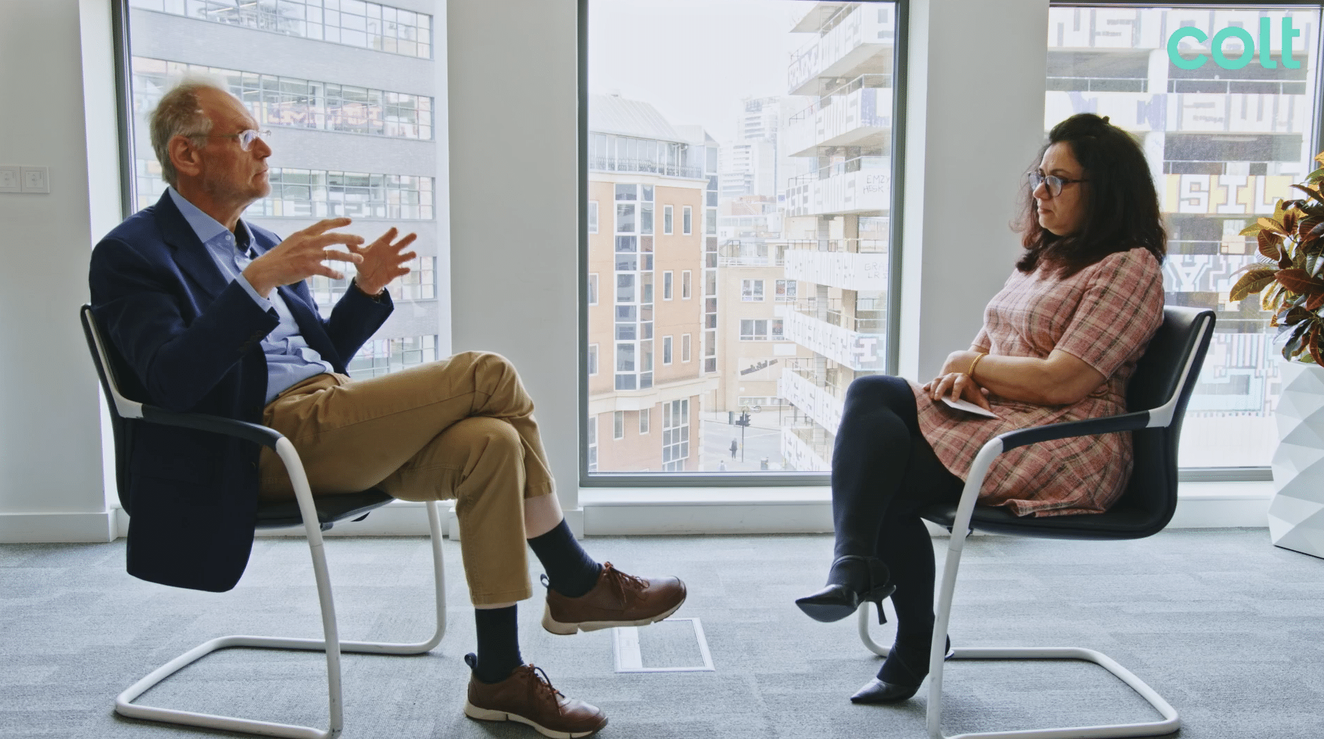  The image shows two people, a man and a woman sitting across from each other having a conversation.